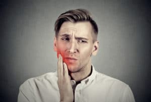 A man experiencing a toothache from an impacted wisdom tooth