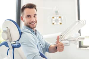 A patient sitting in an orthodontist’s chair giving a thumbs up
