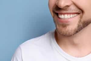 Young man with beautiful smile on grey background