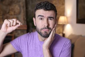 Man looking concerned holding his tooth that has come out, needing replacement option like zygoma implant