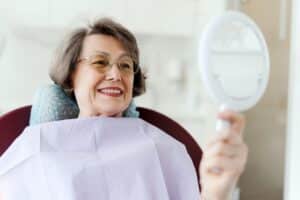 Senior woman admires her new smile after a dental implant.
