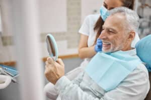 Senior man admires his new smile after recovering from jaw reconstruction.