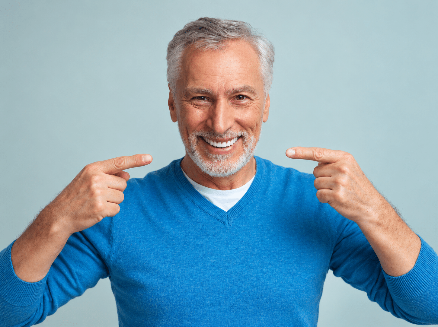 White-haired senior man is pleased with his dental implant results.
